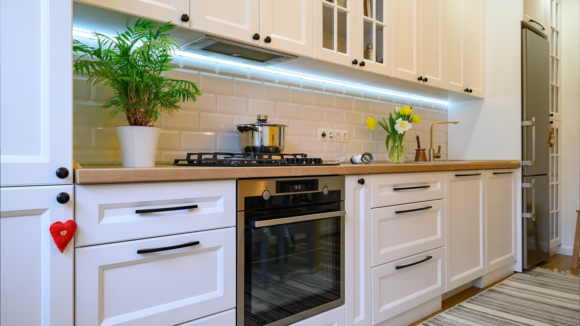 Moderne weiße Küche mit Herd und frischen Blumen auf der Arbeitsfläche